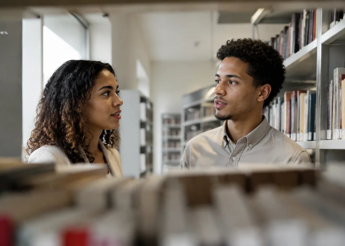 Participantes conversando em pé no corredor entre estantes de livros altas